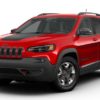 A red jeep cherokee is parked on the street.