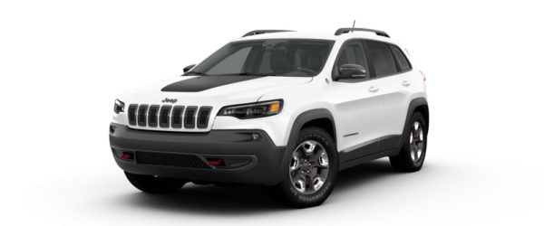 A white jeep cherokee is parked on the street.